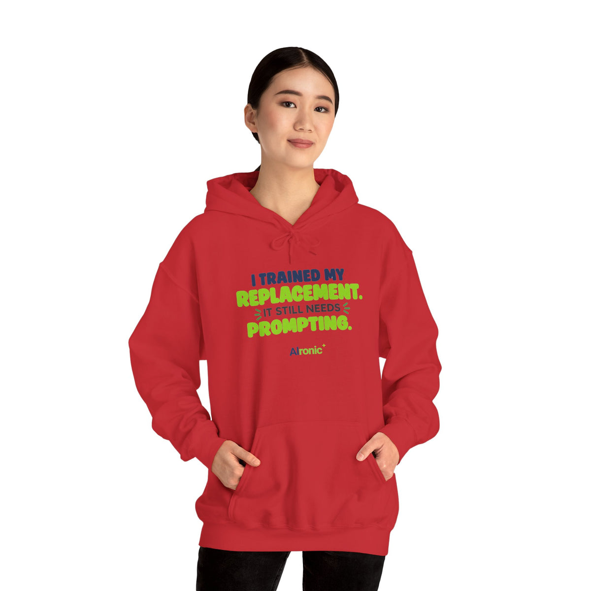 Red hoodie featuring "I trained my replacement. It still needs prompting." AIronic design, modeled front view