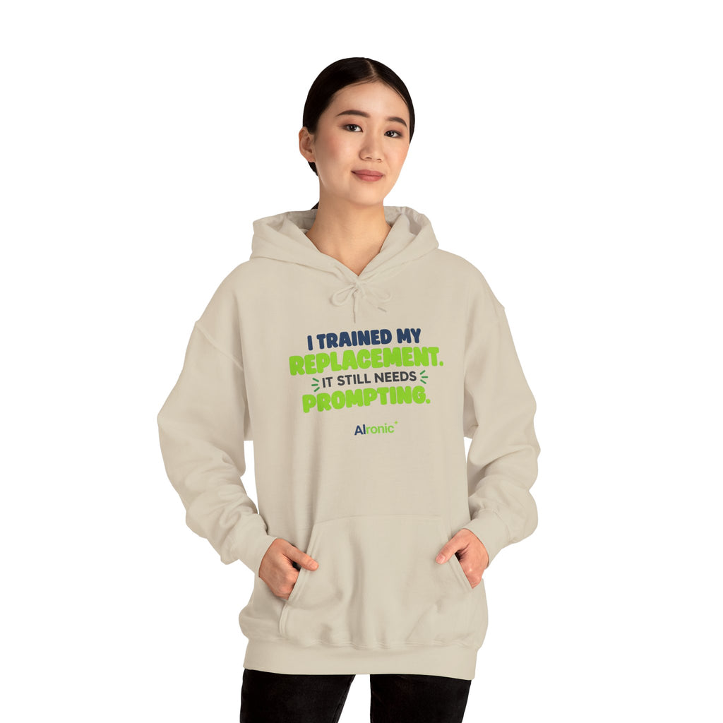 Sand hoodie featuring "I trained my replacement. It still needs prompting." AIronic design, modeled front view