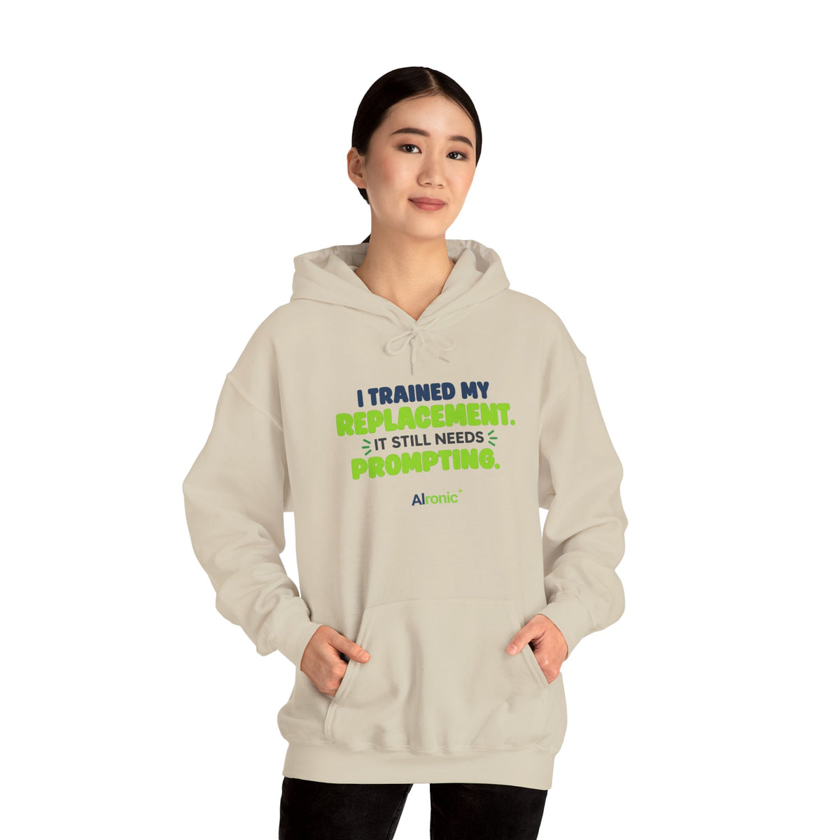 Sand hoodie featuring "I trained my replacement. It still needs prompting." AIronic design, modeled front view