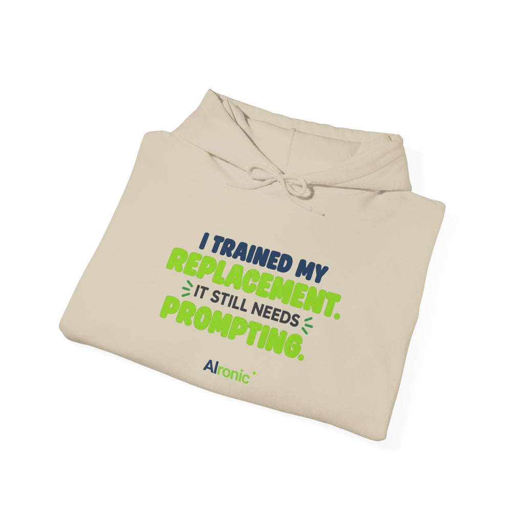 Sand hoodie featuring "I trained my replacement. It still needs prompting." AIronic design, folded detail view